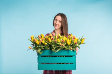 Lale mavi zemin üzerine kutusuyla tutan güzel kadın bahçıvan