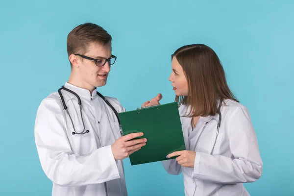파란색 배경에서 논의 하는 젊은 남성과 여성의 의사 — 스톡 사진