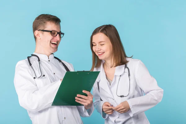 Νέοι άνδρες και γυναίκες γιατροί είναι το γέλιο σε μπλε φόντο — Φωτογραφία Αρχείου