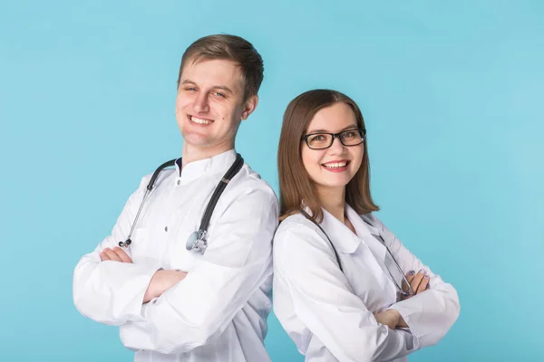 Médicos masculinos y femeninos en batas blancas sobre fondo azul — Foto de Stock