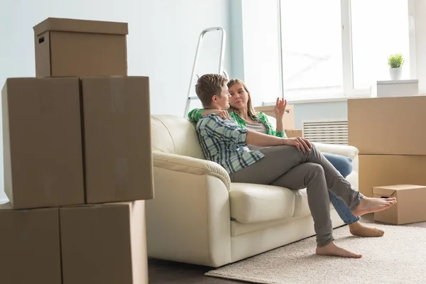 Новый дом, переезд и семейная концепция - Молодая пара сидит на белом диване и что-то обсуждает — стоковое фото
