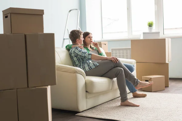 Новый дом, переезд и семейная концепция - Молодая пара сидит на белом диване и что-то обсуждает — стоковое фото