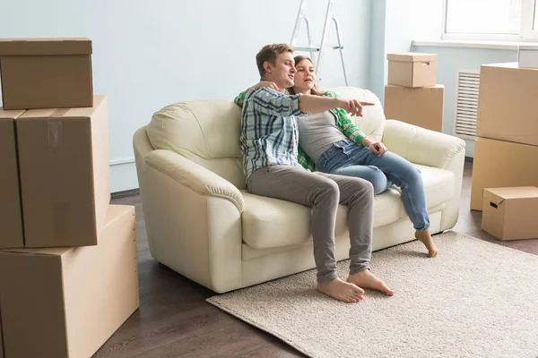 Neues Zuhause, Umzug und Immobilien - junges Paar sitzt auf der Couch und redet miteinander — Stockfoto