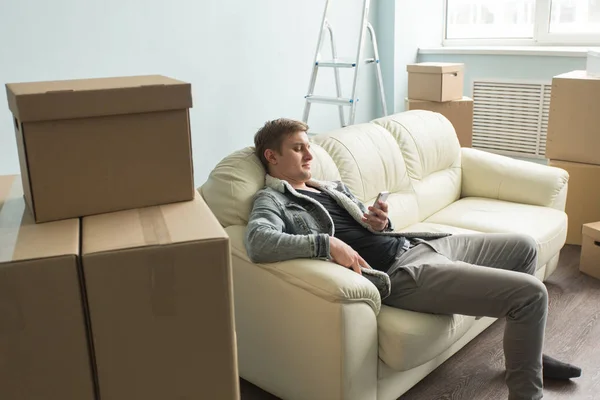 移动过程, 房地产和新的家庭概念-疲惫的家伙坐在沙发上的空房间 — 图库照片