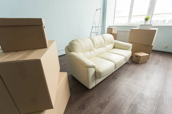 Áthelyezés, a mozgó és a real estate koncepció-egy új fehér kanapé üres szobában közötti összegű dobozok — Stock Fotó