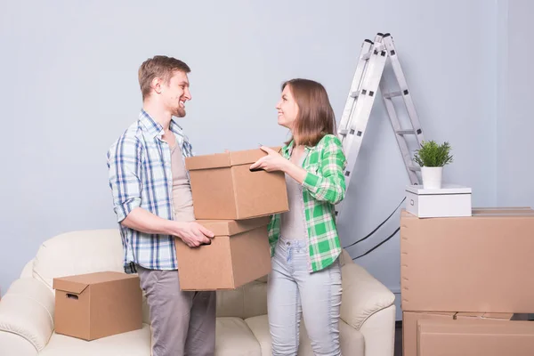 Семья, новая квартира, эмоции и концепция переезда - пара молодых счастливых людей, держащих коробки. Переезд в новую квартиру — стоковое фото