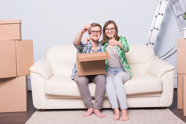 Переезд, переезд и новая концепция дома - молодая пара веселится на диване в окружении коробок — стоковое фото