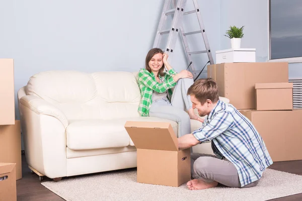 Переїзд, нова квартира та концепція переїзду - молодий чоловік допомагає дружині розпакуватися — стокове фото