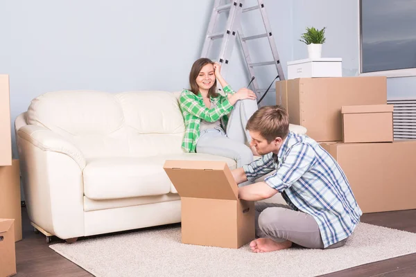 Movendo-se, novo apartamento e conceito de realocação - jovem casal no quarto cercado por caixas ter uma conversa fiada . — Fotografia de Stock