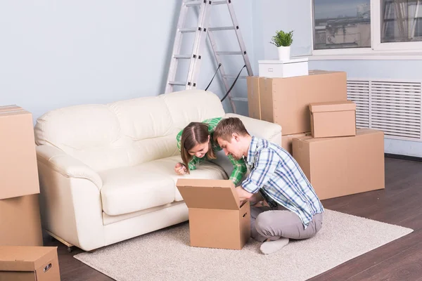 Umzugs- und Immobilienkonzept - glückliches Paar hat Spaß beim Auspacken von Kartons im neuen Zuhause — Stockfoto