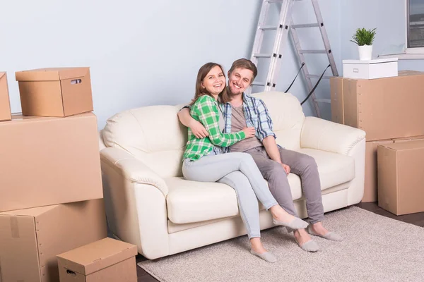 Новый дом, переезд и переезд - симпатичный молодой человек обнимает сидящую на диване женщину — стоковое фото