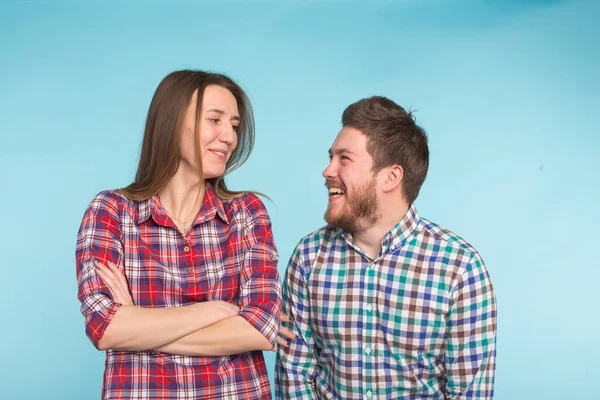 Cute funny couple in checkered shirts laughing on blue background