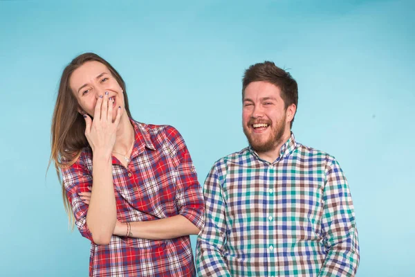 Bonito casal engraçado em camisas quadriculadas rindo no fundo azul — Fotografia de Stock