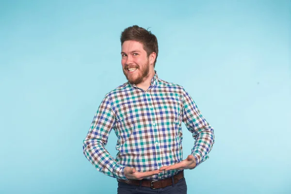 Emoción, gente y concepto divertido - Joven hombre guapo riendo sobre fondo azul — Foto de Stock