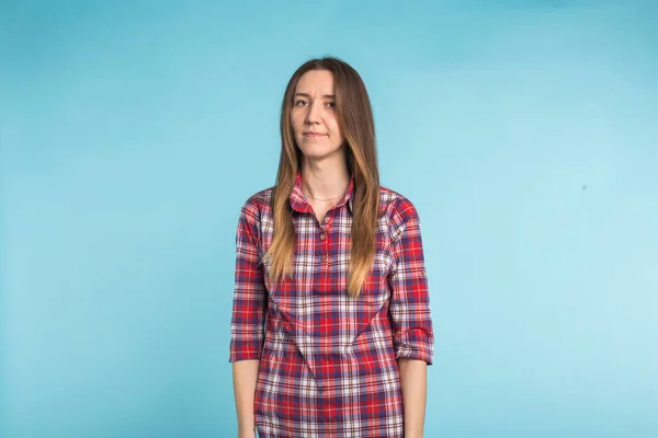 Jovem mulher europeia de pé com rosto sério em fundo azul — Fotografia de Stock