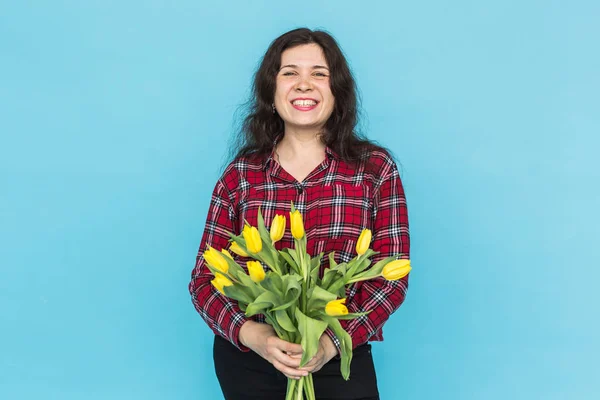 Bouquet de tulipes jaunes sur les mains des femmes sur fond bleu — Photo