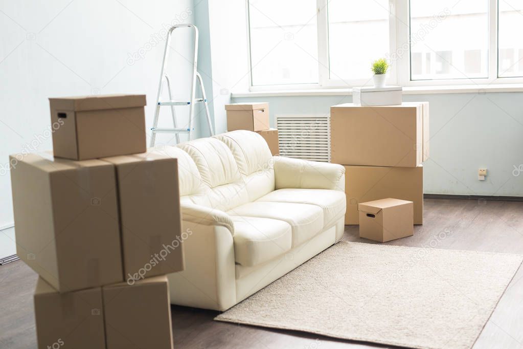 Relocation, new home and real estate concept - Moving boxes and sofa in empty room