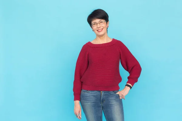 Mode, mensen en stijl concept - mooie midden leeftijd vrouw in rode trui en glazen op blauwe achtergrond met kopie ruimte — Stockfoto