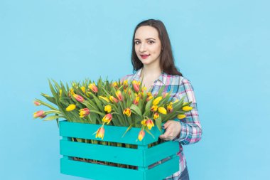 Lale mavi zemin üzerine kutusuyla tutan güzel kadın bahçıvan