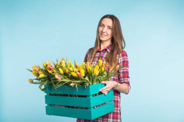 Lale mavi zemin üzerine kutusuyla tutan mutlu beyaz genç kadın.
