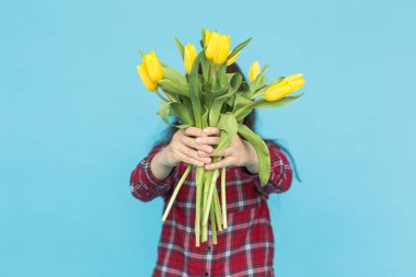 Bayram, çiçekler ve insanlar kavramı - komik kızla buket lale mavi bir arka plan üzerinde poz ellerinde ekose gömlekli
