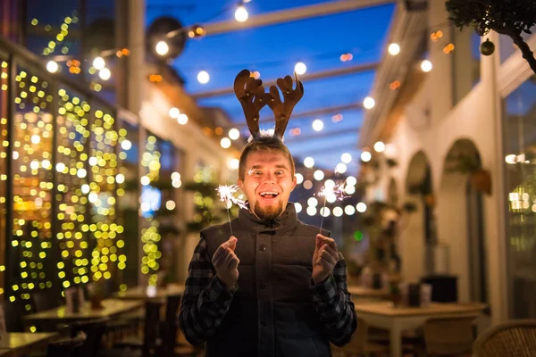 Christmas and holiday concept - Happy man in Christmas deer costume with sparkler