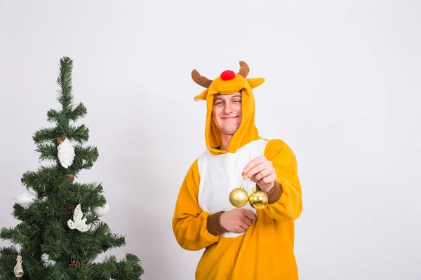 Joke, christmas, people concept - man in deer costume decorating xmas tree on white background — Stock Photo, Image