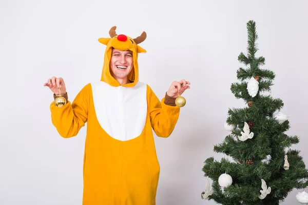 Skämt, jul, folk koncept - mannen i rådjur kostym dekorera xmas träd på vit bakgrund — Stockfoto