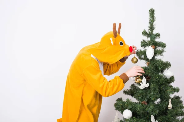 Piada, Natal, conceito de pessoas - homem de traje de veado decorando árvore de xmas no fundo branco — Fotografia de Stock