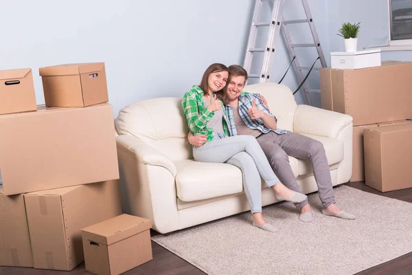 Концепция переезда и недвижимости - Счастливая пара целуется на диване в своей новой квартире — стоковое фото