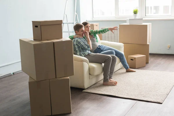 Новый дом, переезд и недвижимость - Счастливая пара сидит на диване и обсуждает новую квартиру — стоковое фото