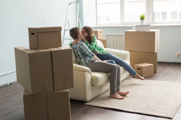 Новый дом, недвижимость и семья, пара - молодая пара развлекается на диване в окружении коробок для переезда — стоковое фото