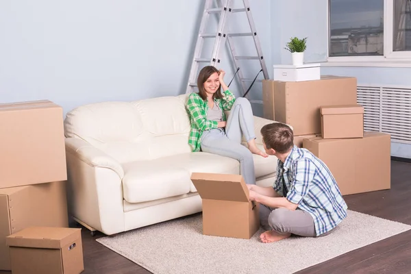 Переезд, новая квартира и переезд - Молодой человек помогает жене распаковывать вещи — стоковое фото
