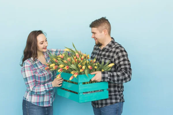 Szczęśliwy Kwiaciarnie mocowanie tulipany w duże drewniane pudełko na niebieskim tle — Zdjęcie stockowe
