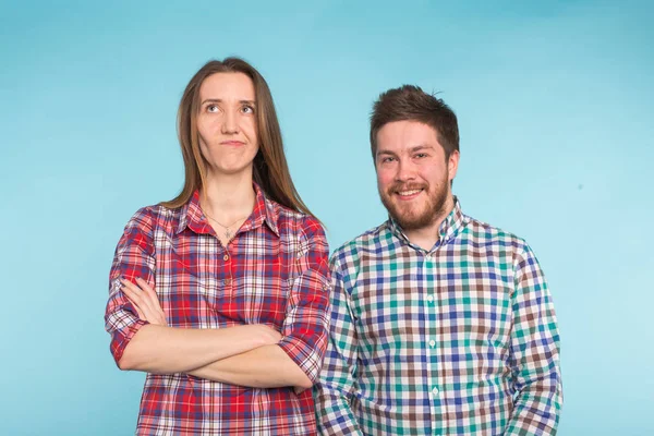 Bonito casal engraçado em camisas quadriculadas rindo no fundo azul — Fotografia de Stock