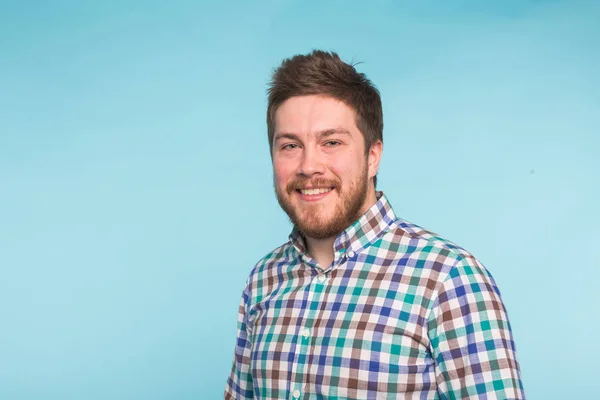 Emoción, gente y concepto divertido - Joven hombre guapo riendo sobre fondo azul — Foto de Stock