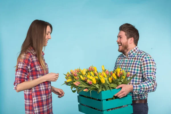 Szczęśliwy Kwiaciarnie mocowanie tulipany w duże drewniane pudełko na niebieskim tle — Zdjęcie stockowe