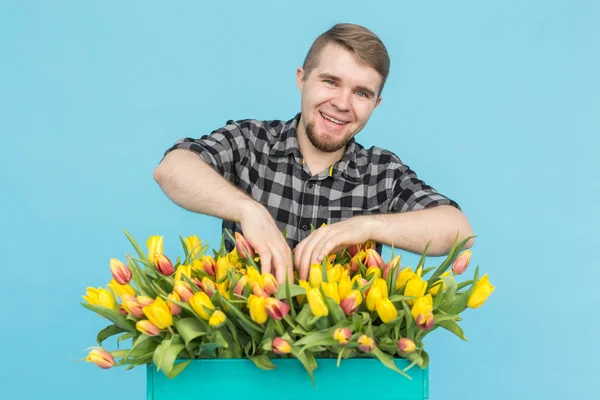 Florística, férias e conceito de pessoas - Jardineiro homem que fixa um buquê de tulipas no fundo azul . — Fotografia de Stock