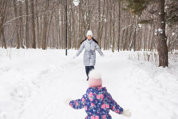 Семья, дети и природа - мать с дочерью развлекаются в зимнем парке — стоковое фото