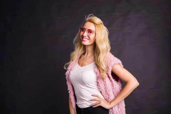 Fashion and beauty concept - portrait of blond model dressed in white shirt and pink cardigan over black background with copy space — Stock Photo, Image