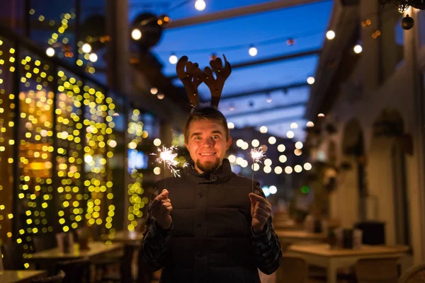 Concepto de Navidad y vacaciones - Hombre feliz en traje de ciervo de Navidad con bengala — Foto de Stock