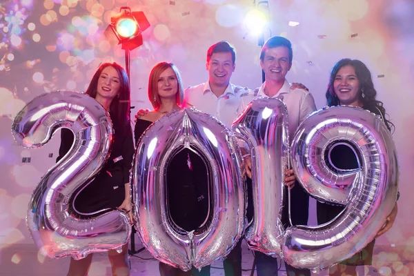 Conceito de festa de Ano Novo. Grupo de jovens amigos segurando números coloridos de prata 2019 e jogando confete — Fotografia de Stock