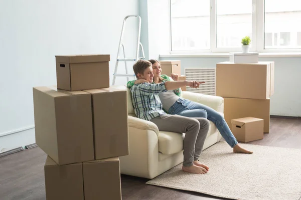 Переезд, новый дом и концепция людей - красивая счастливая влюбленная пара, сидящая в пустой квартире среди коробок — стоковое фото
