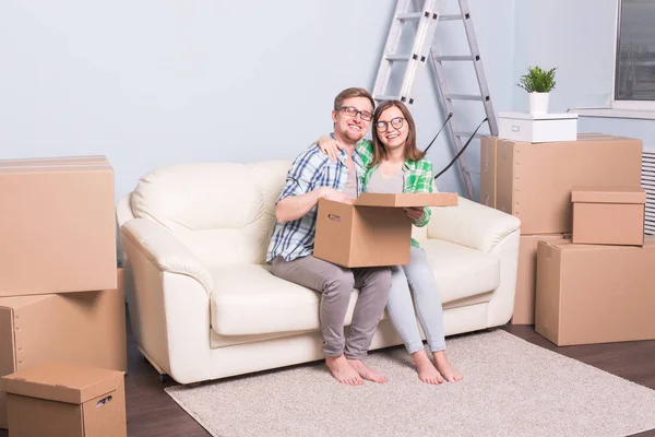 Новая квартира, переезд и переезд - счастливая пара сидит на диване в своей новой квартире — стоковое фото