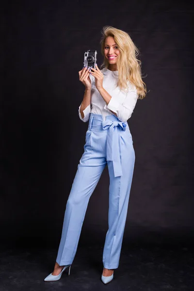 Concepto de moda, fotógrafo y belleza - Retrato de modelo rubio en camisa blanca sosteniendo fotocámara retro sobre fondo oscuro —  Fotos de Stock