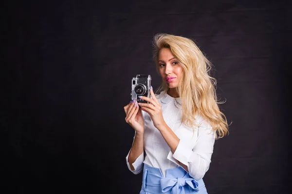 Свободное время, мода и люди концепция - молодая блондинка делает фото и улыбается на черном фоне с копировальным пространством — стоковое фото