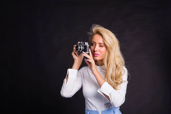 Fotografování, módy a lidé koncept - mladá blond žena dělat fotografie z něčeho na černém pozadí s kopií prostor — Stock fotografie