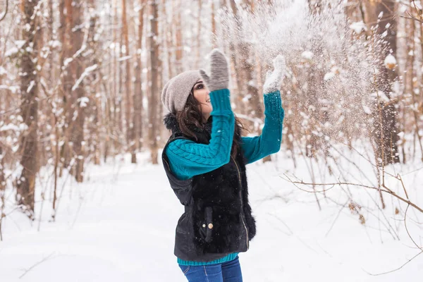 Saison, loisirs et concept de personnes - la jeune femme est heureuse et jette de la neige dans la nature hivernale — Photo