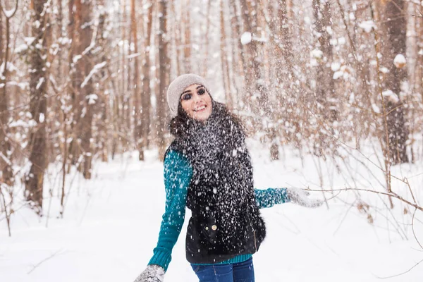 幸せな若い女が屋外の雪の森で雪で遊ぶ — ストック写真