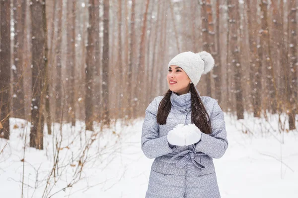 Noël, vacances et concept de saison - Jeune belle femme souriante tenant la neige dans les mains en hiver à l'extérieur — Photo